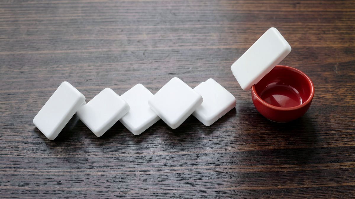 Dominos falling in a precise mechanical chain, each one triggering the next with perfect accuracy, but the final domino knocking over something unintended, representing systems that execute perfectly but produce unintended outcomes