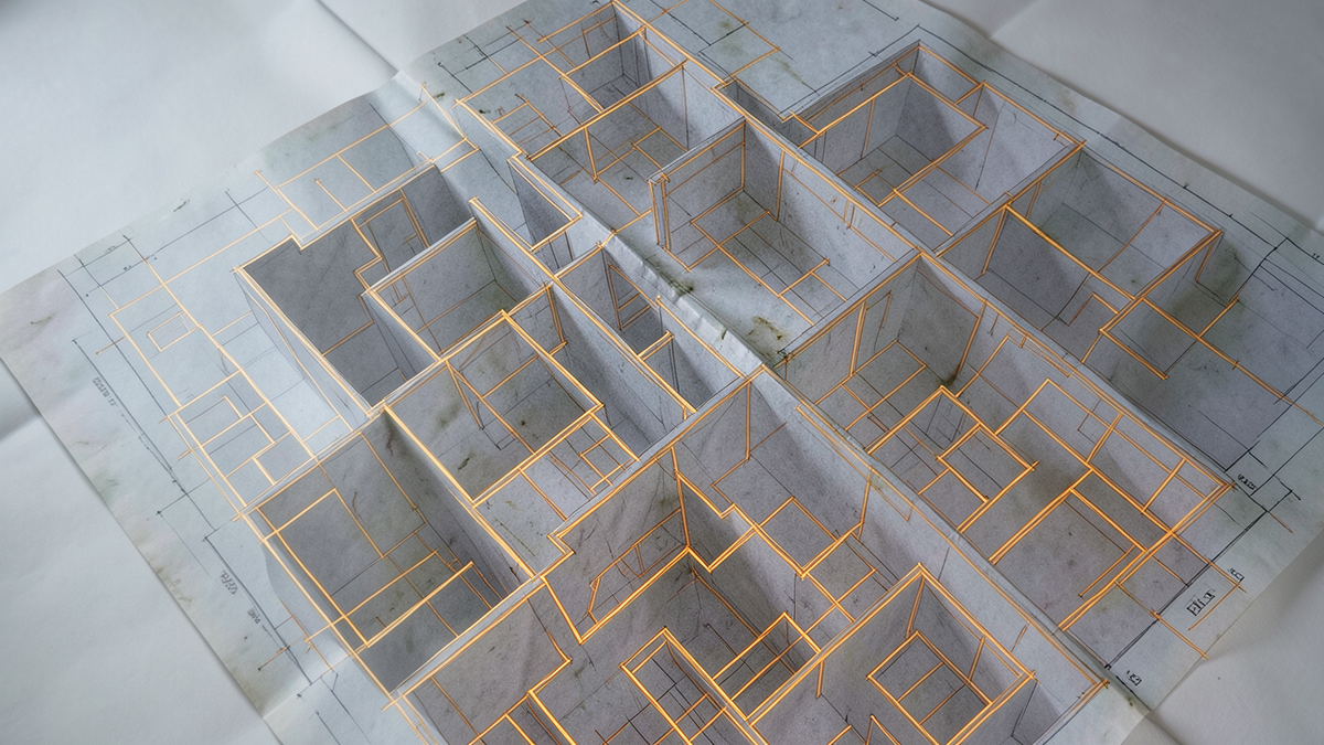 A faded architectural diagram overlaid on a labyrinth that has changed shape, the map no longer matching the territory